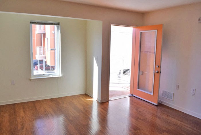 an empty living room with an orange door and a window
