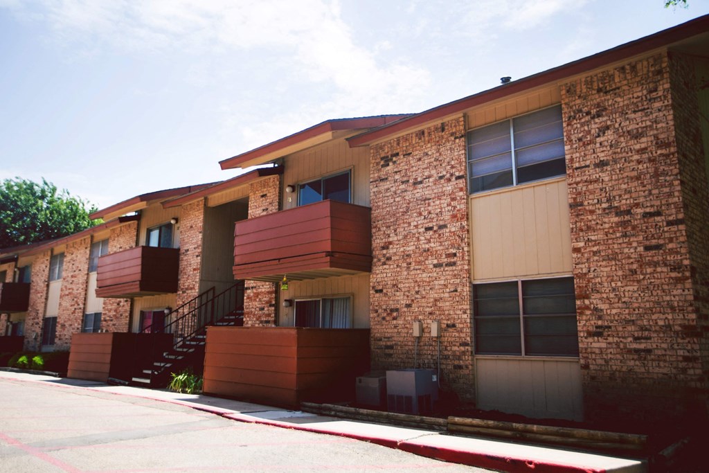 the side of a building with stairs and a sidewalk