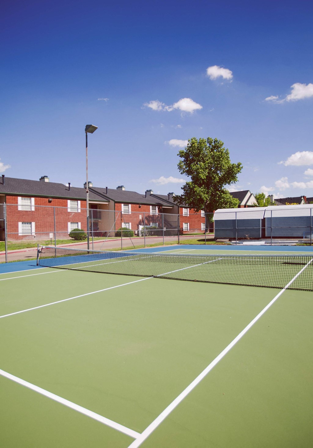 a tennis court with apartments in the background