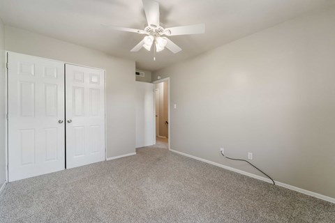 A room with a ceiling fan and carpeted floor.