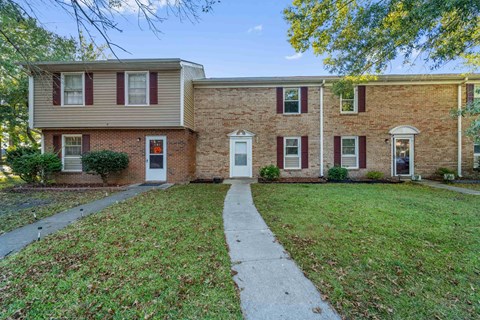 A brick house with a red door and a white door.