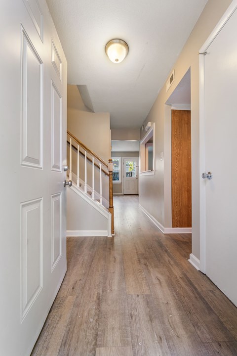 A long hallway with white walls and wood floors.