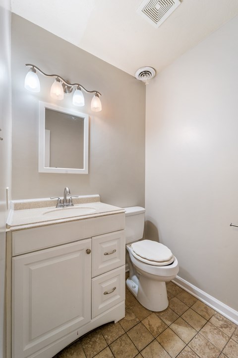 A white bathroom with a toilet, sink, and mirror.