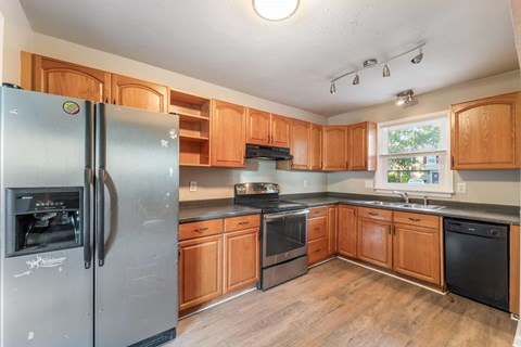 A kitchen with wooden cabinets and a stainless steel refrigerator.