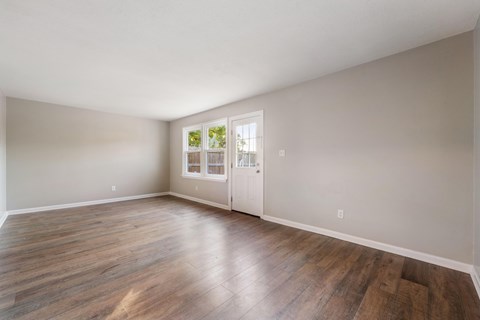 A room with wooden floors and a door leading to a balcony.