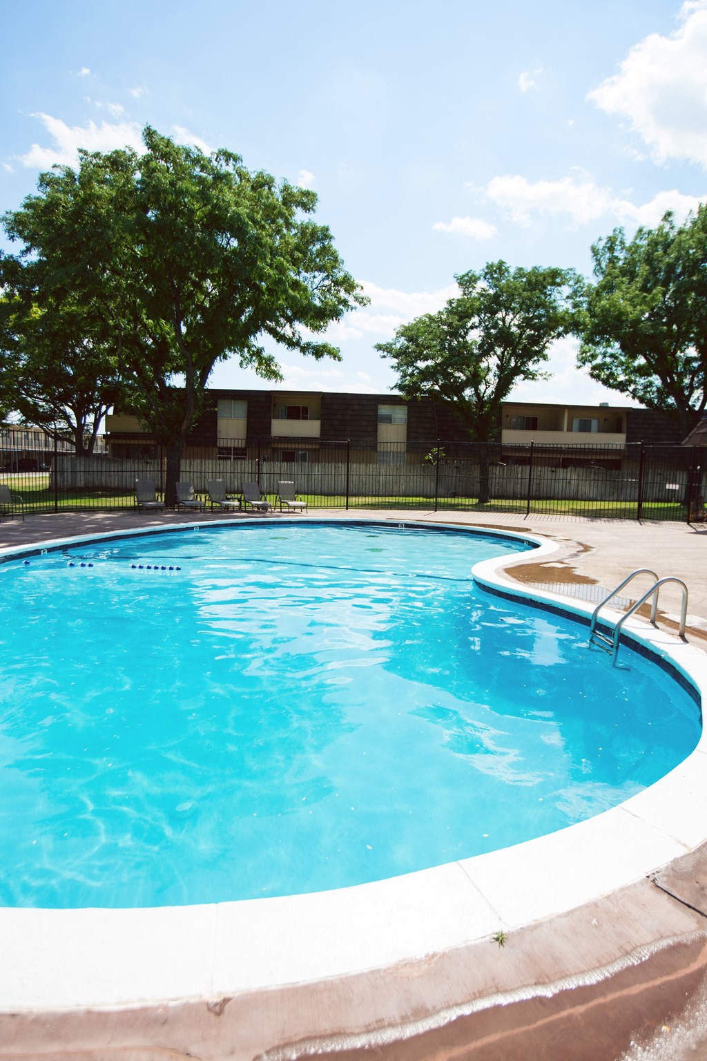 a swimming pool with trees and a black fence around it