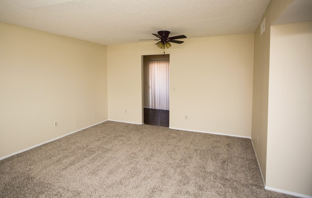 an empty living room with carpet and a ceiling fan