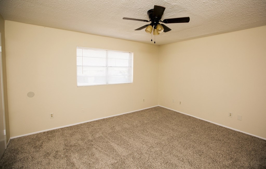 an empty room with a ceiling fan and a window
