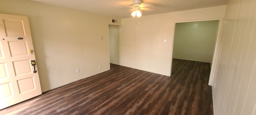 an empty living room with wood flooring and a ceiling fan
