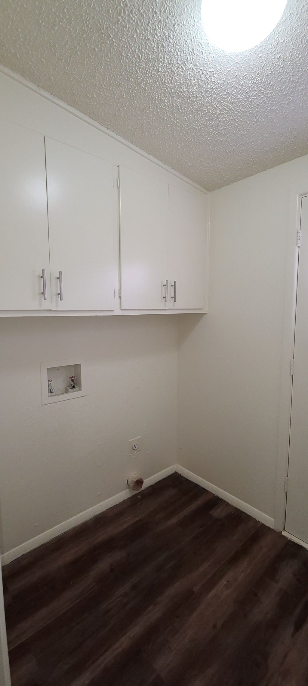 an empty room with white cabinets and a wood floor