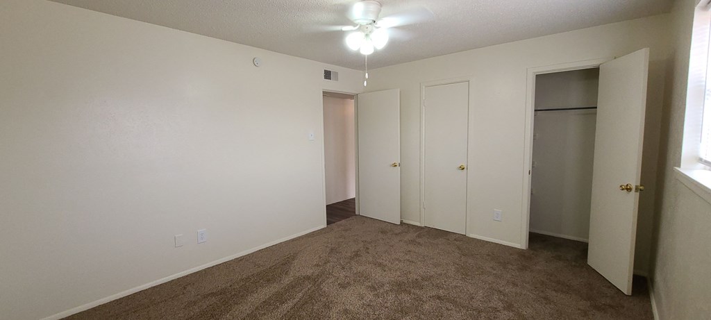 an empty living room with carpet and a door to a closet