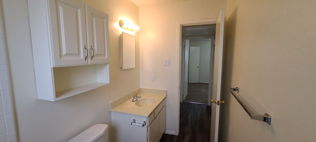 a bathroom with a sink and a mirror and a door to a hallway