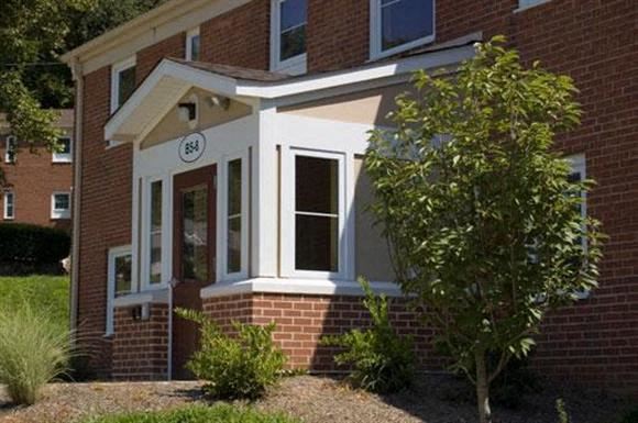 a red brick house with a porch and a clock on it