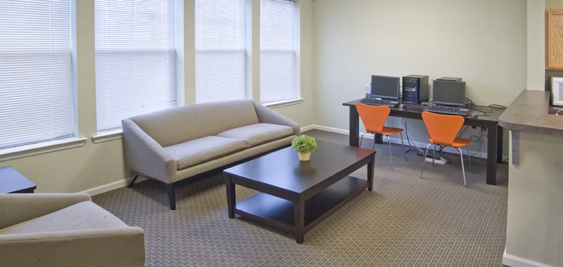 a living room with a couch and a table with computers