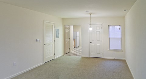 an empty living room with a door to a hallway