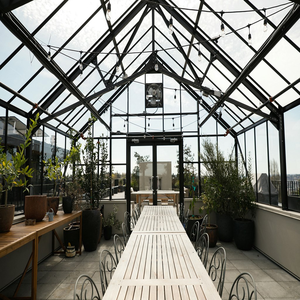 a patio with tables and chairs in a greenhouse with glass walls