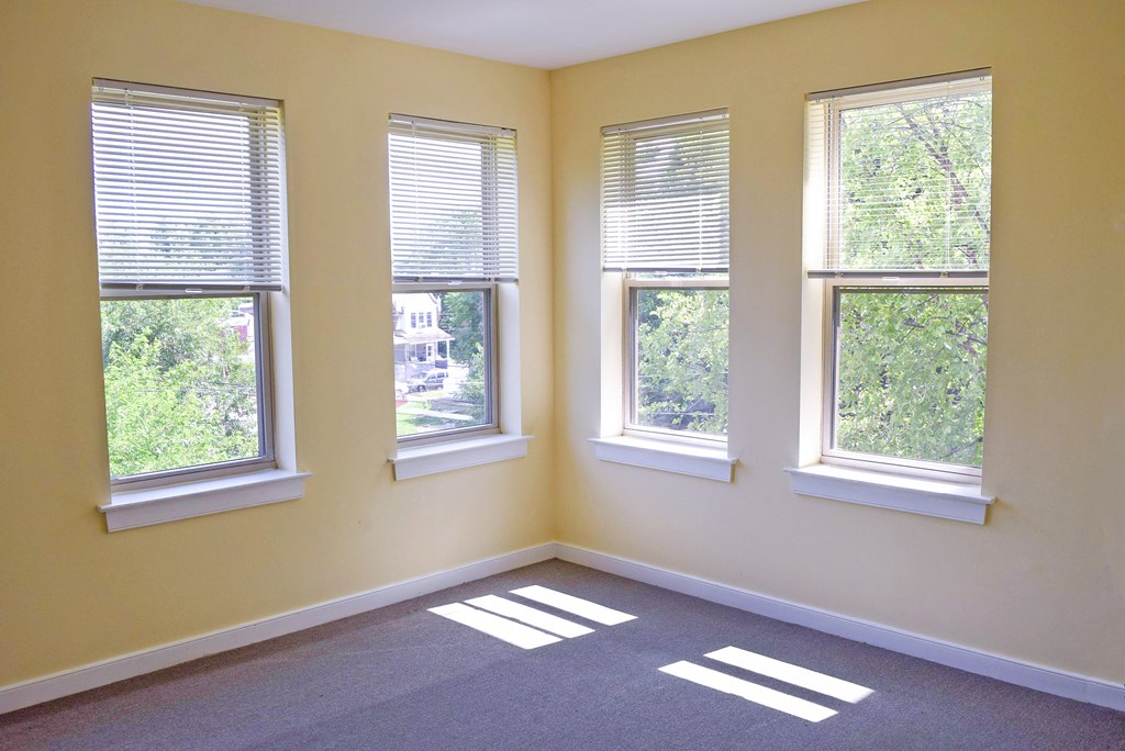 an empty room with three windows and a carpet