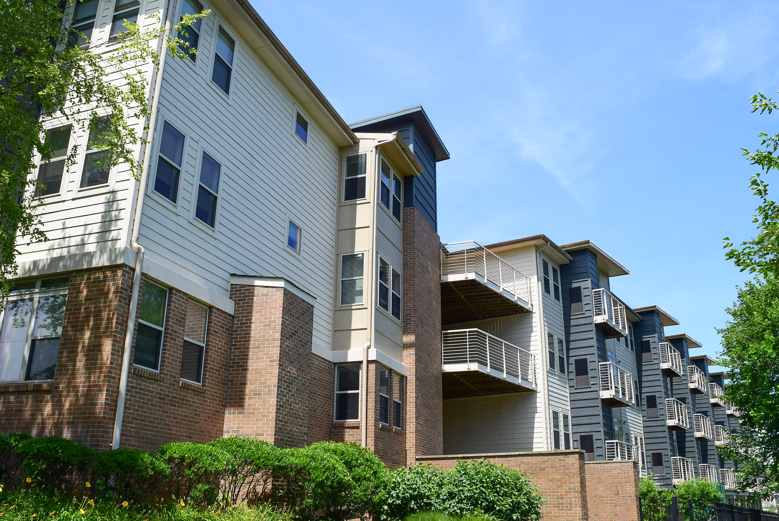 an apartment building with brick and white siding and balconies