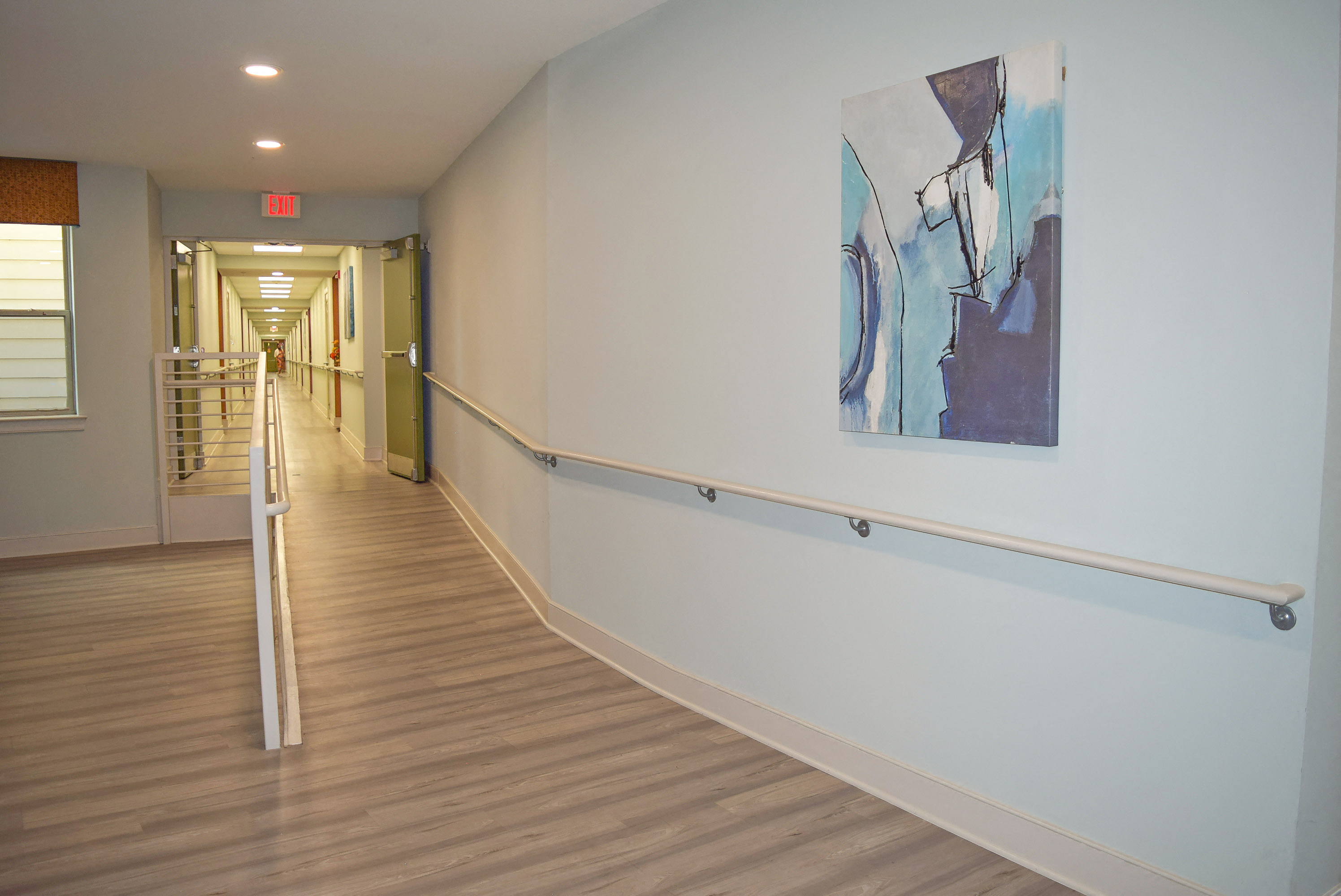 a hallway with a painting on the wall and a rail on the floor