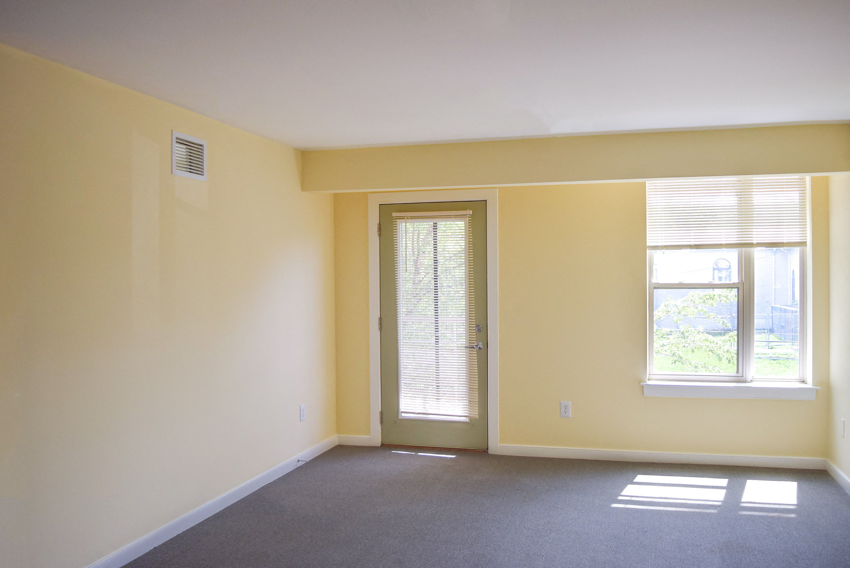 an empty living room with a door and window