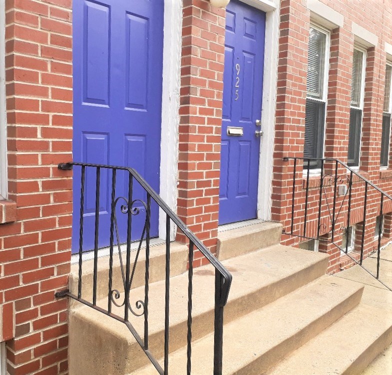 two blue doors on a brick building with stairs