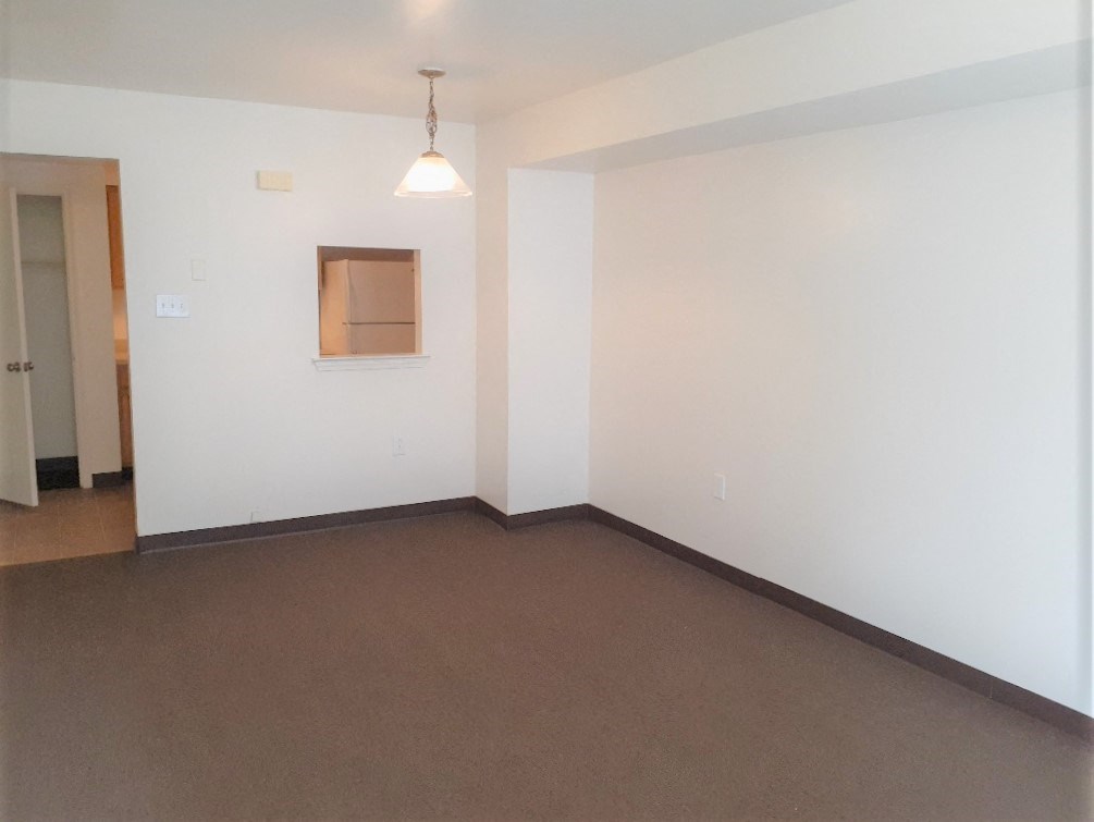 an empty living room with white walls and brown carpet