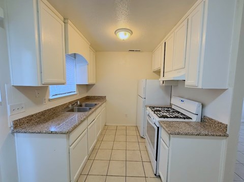 A kitchen with white cabinets and granite countertops.