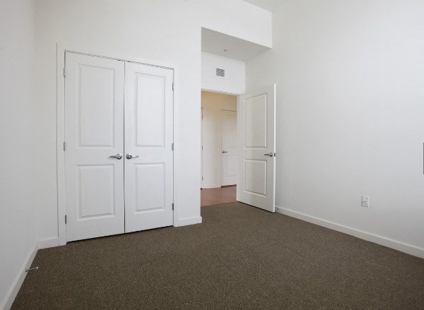 an empty bedroom with white doors and carpeting