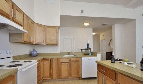 an empty kitchen with wooden cabinets and white appliances