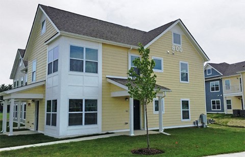 a yellow house with a tree in front of it
