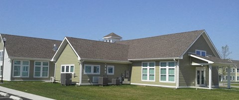 a yellow house with a brown roof and a lawn