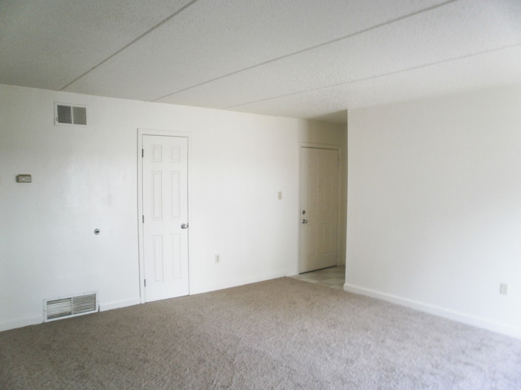 an empty living room with white walls and a white door