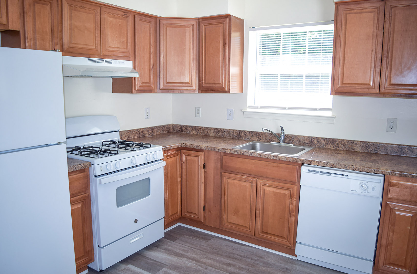an empty kitchen with white appliances and wooden cabinets