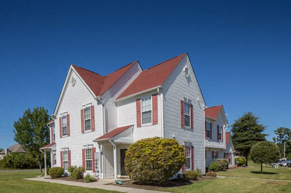 a white house with a red roof on a lawn