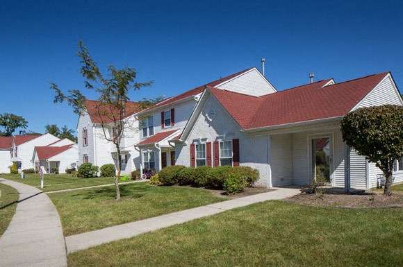 a white house with a red roof and a sidewalk