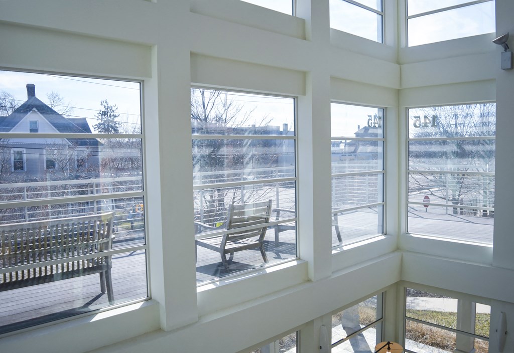 the view from the living room window of a porch with a chair and a bench
