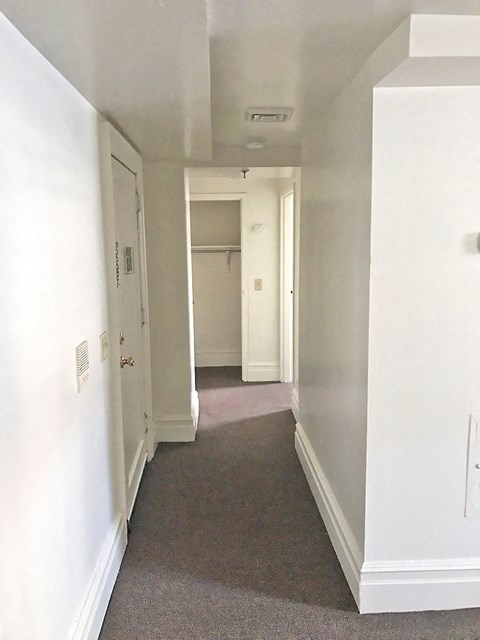 a hallway with white walls and a carpet and a white door