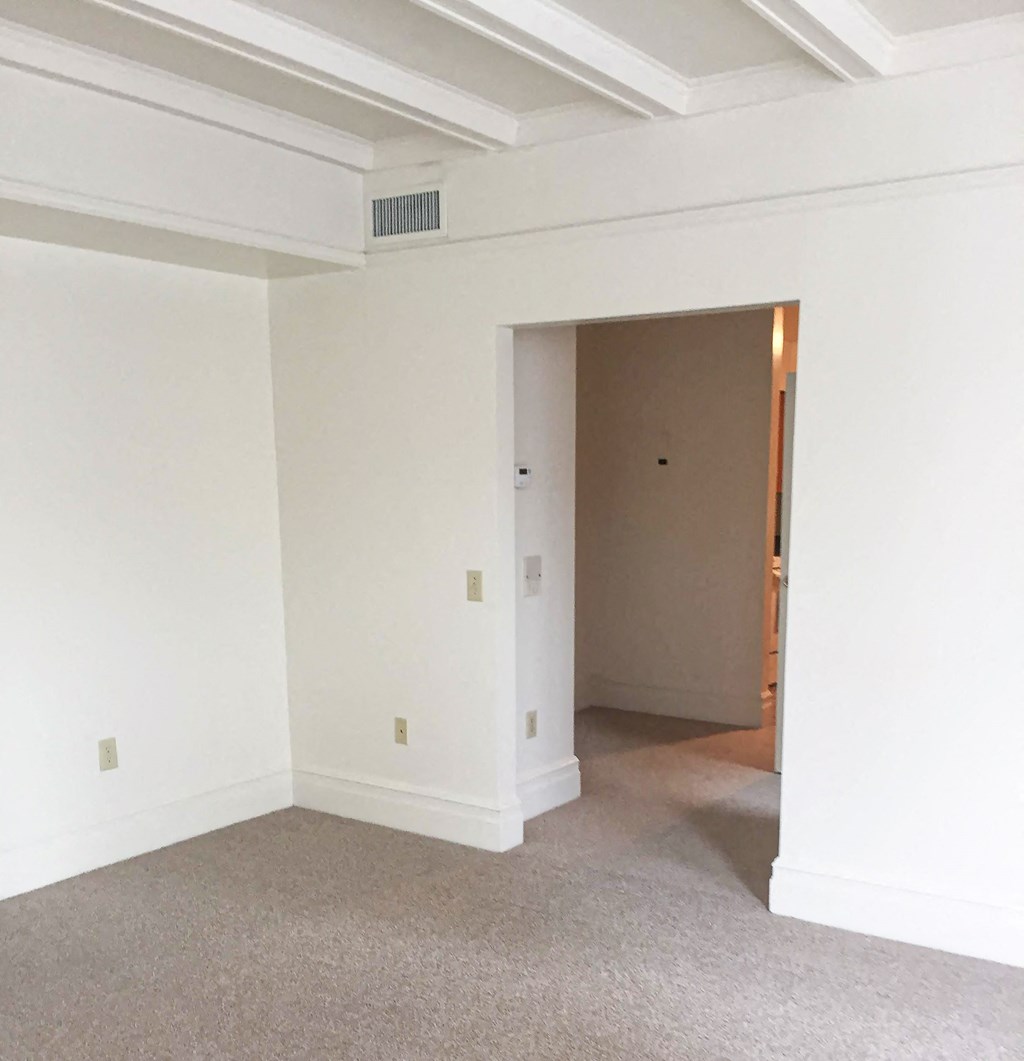an empty living room with white walls and a door to a hallway