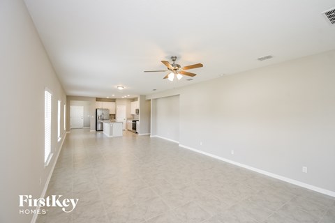 an empty living room with a ceiling fan and a large tile floor