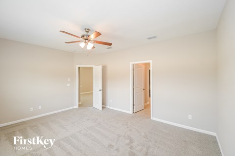a spacious living room with carpet and a ceiling fan