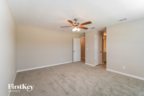 a spacious living room with carpet and a ceiling fan