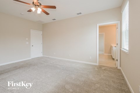 a spacious living room with carpet and a ceiling fan