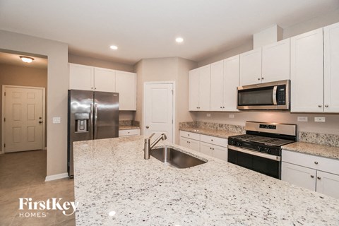a large kitchen with white cabinets and granite counter tops