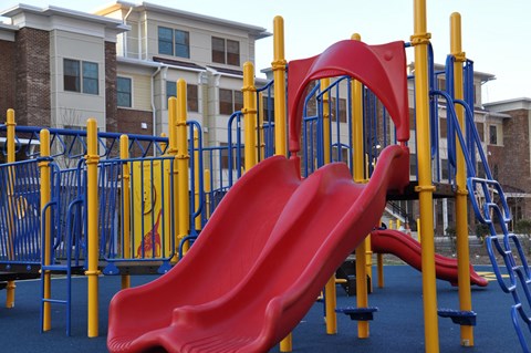 a playground with a red slide and a blue fence