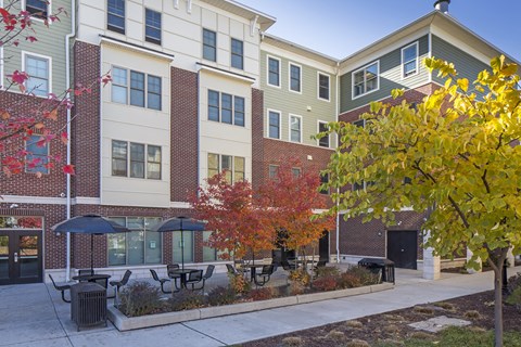 a courtyard with tables and umbrellas in front of a building