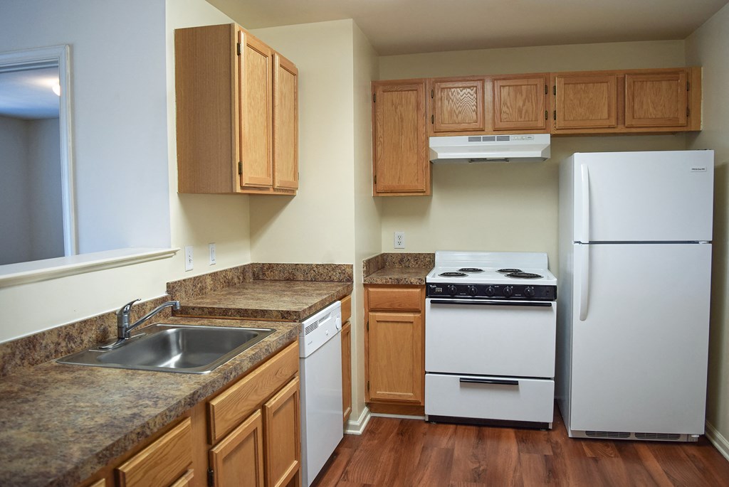 an empty kitchen with white appliances and wooden cabinets
