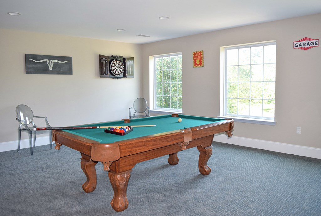 a game room with a pool table and two windows