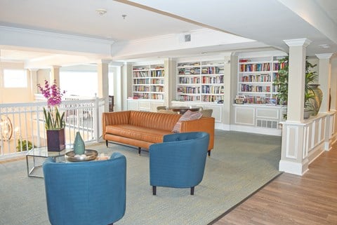a living room with couches and chairs and a book shelf