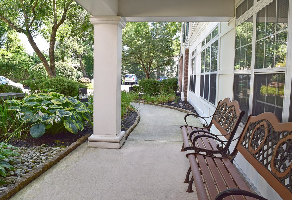 a front porch with benches and a sidewalk