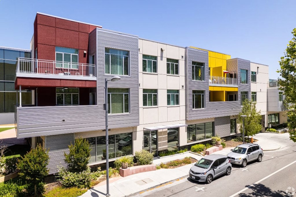 a row of apartment buildings with cars parked in front of them
